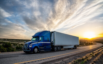 Blue Tractor Trailer on highway at sunset state trucking permits