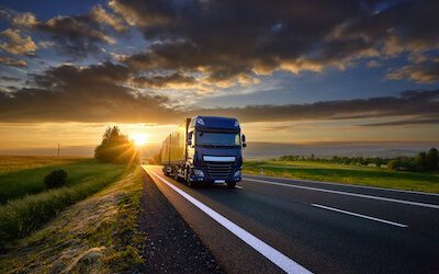 Black tractor trailer on road in plains at sunset UCR REGISTRATION