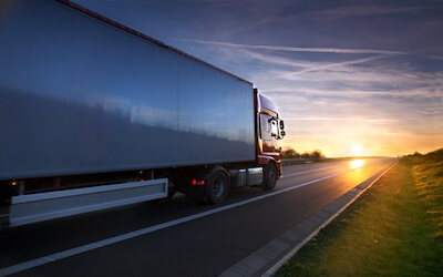 Red truck white trailer on highway at sunset IFTA tax