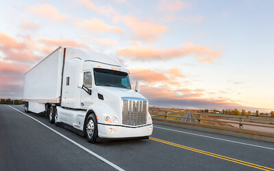 White tractor trailer on highway at sunset MC number