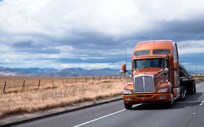 Red truck driving on highway with New York state truck permit